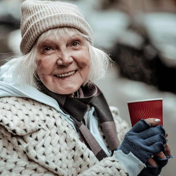 Señora mayor con ropa de invierno y vaso rojo en la mano