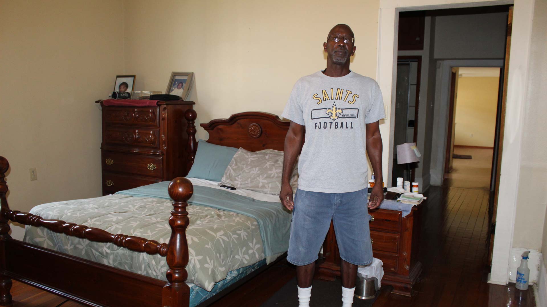 Hombre en shorts y camiseta de los New Orleans Saints parado en su cuarto