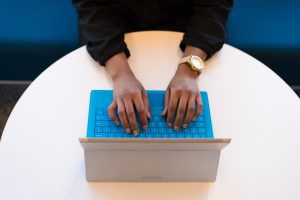 A person types on a Surface tablet with a blue keyboard cover
